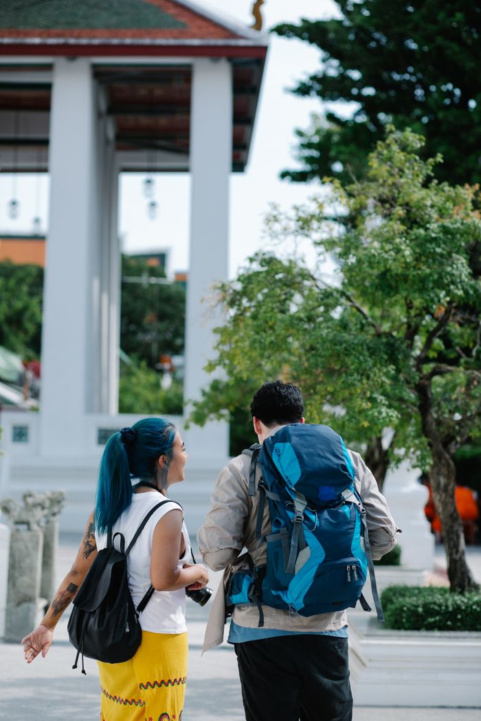 A couple with backpacks enjoying a summer day in an urban setting, exploring the city together.